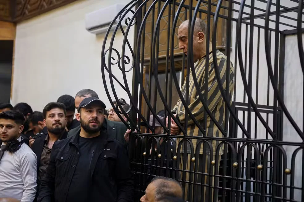 Atef Najib, primo de Bashar al-Assad e ex-chefe do Departamento de Segurança Política de Daraa, aparece em jaula durante julgamento no Palácio da Justiça, em Damasco, na Síria. Foto de 26 de abril de 2026. — Foto: AP Photo/Ghaith Alsayed/Arquivo