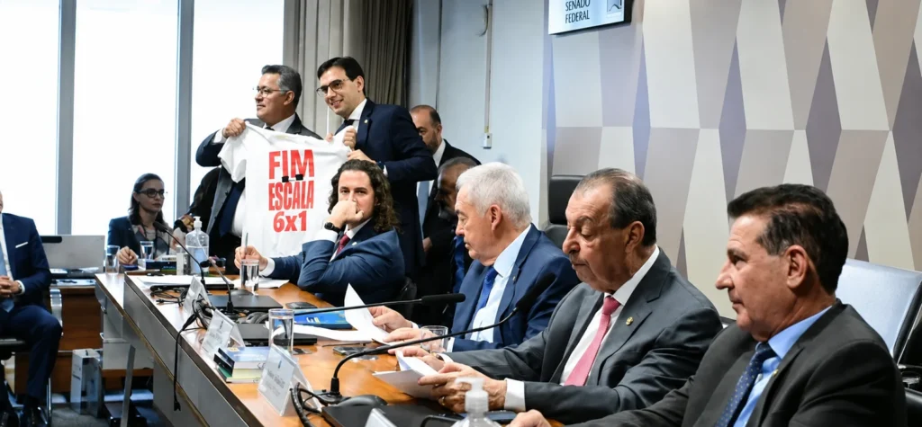 A Comissão de Constituição e Justiça (CCJ) do Senado aprovou nesta quarta-feira (2) o texto-base da PEC que prevê o fim da escala 6x1. A proposta estabelece uma jornada de trabalho de até 40 horas semanais, com dois dias de descanso remunerado e sem redução salarial. O texto agora está pronto para ser analisado pelo plenário do Senado. Para ser aprovado, precisa receber pelo menos 49 votos favoráveis em dois turnos. A PEC 221/2019 já havia sido aprovada pela Câmara dos Deputados e avançou no Senado após um acordo entre o presidente Luiz Inácio Lula da Silva e o presidente do Congresso, Davi